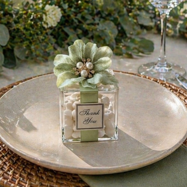 Decorative table setting with a small perfume bottle, flowers, and candles on a table.