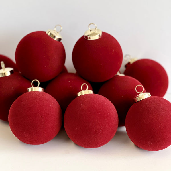 Red Christmas ornaments with gold bases on a white background