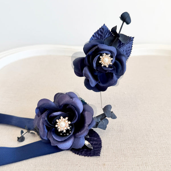 Navy blue floral hair accessories with pearl centers on a white background
