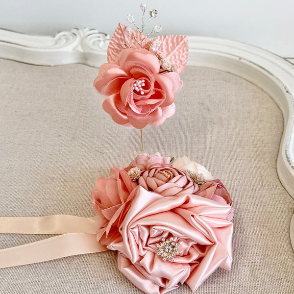Pink floral headband and hair clip set on a textured surface with a decorative mirror in the background.