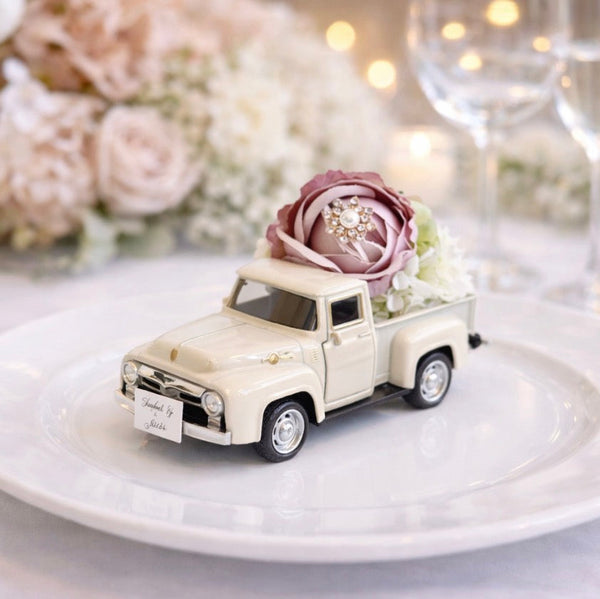 Decorative miniature truck with flowers on a white plate against a floral background