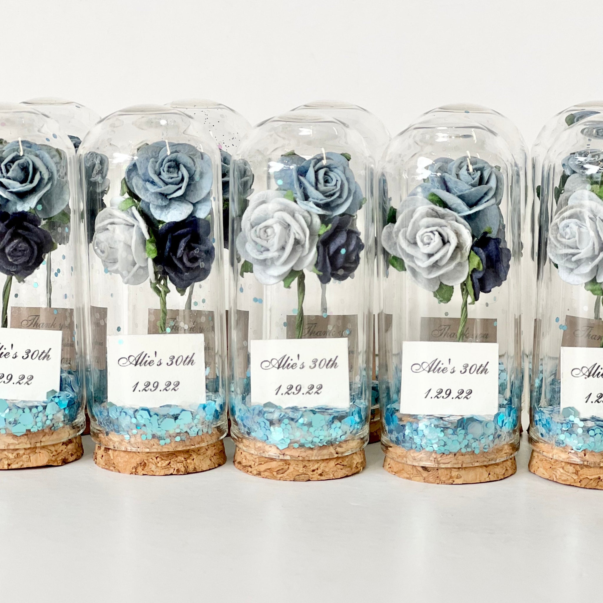 Set of decorative bottles with preserved flowers and labels on a white background