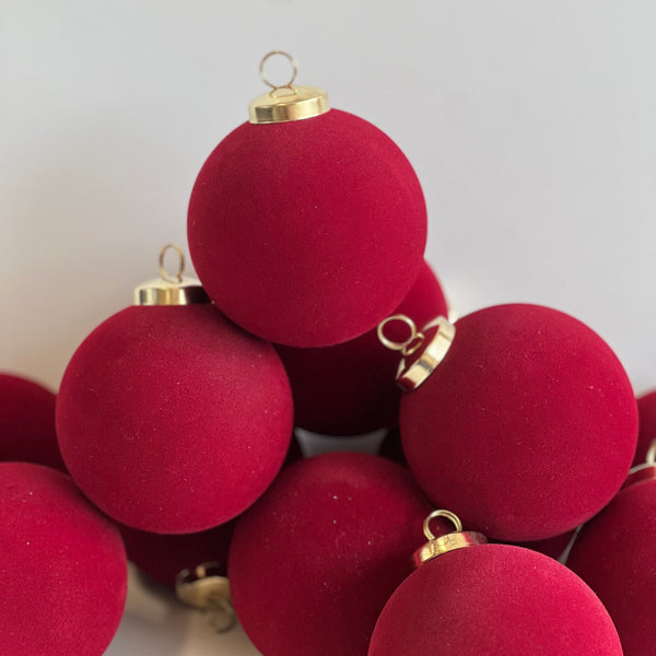 Red Christmas ornaments with gold bases on a light gray background