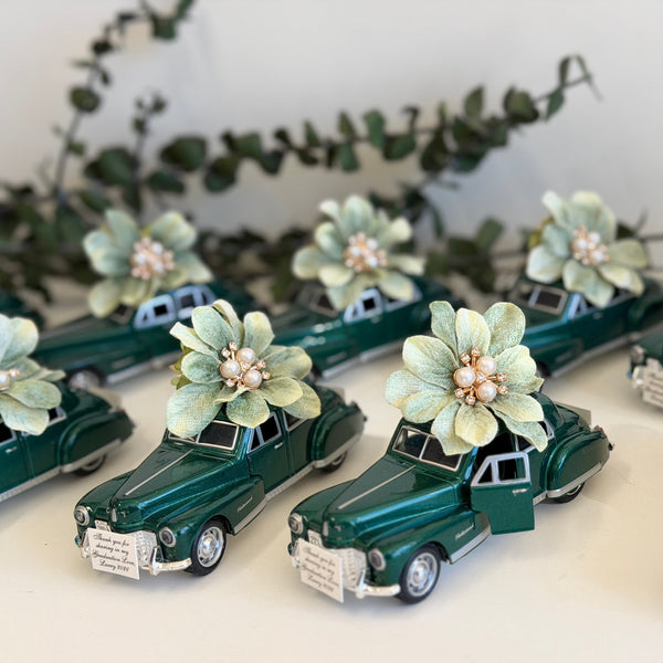 Collection of miniature green cars decorated with flowers on a white surface.