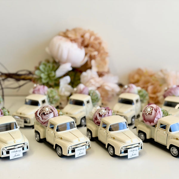 Collection of small model trucks with floral decorations on a white surface.
