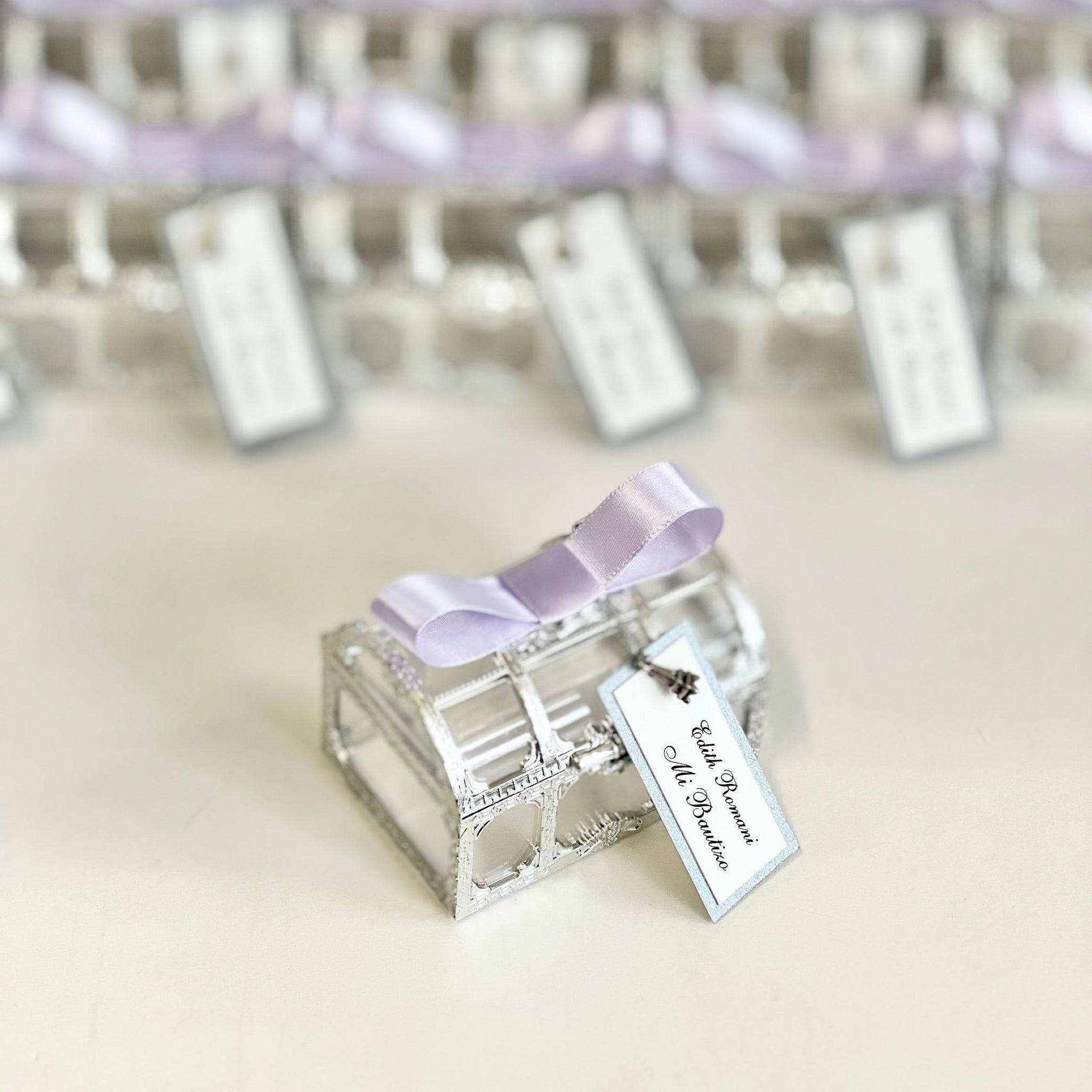 Silver decorative box with a purple ribbon and tag on a light background
