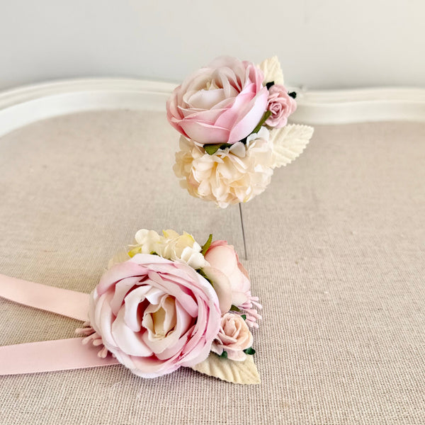 Floral headband and corsage set on a beige surface with a light gray background