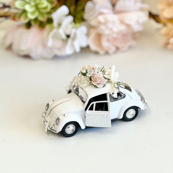 Decorative toy car with flowers on a white surface