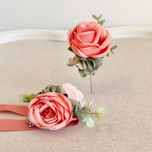Two pink flower corsages on a textured surface with a light background