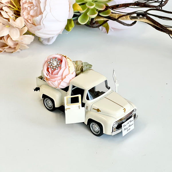 Model car with flowers and a ring on a white surface with flowers in the background
