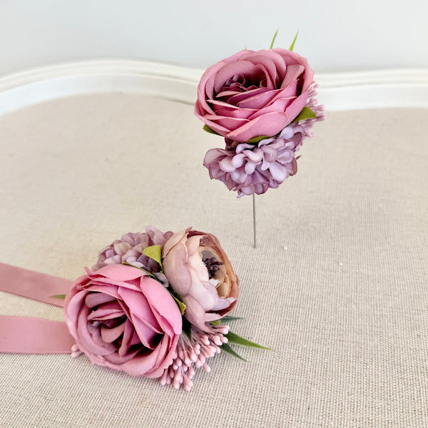 Two floral hair accessories with pink flowers and ribbons on a beige surface.
