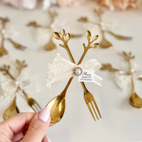 Gold spoon and fork with decorative elements on a white surface