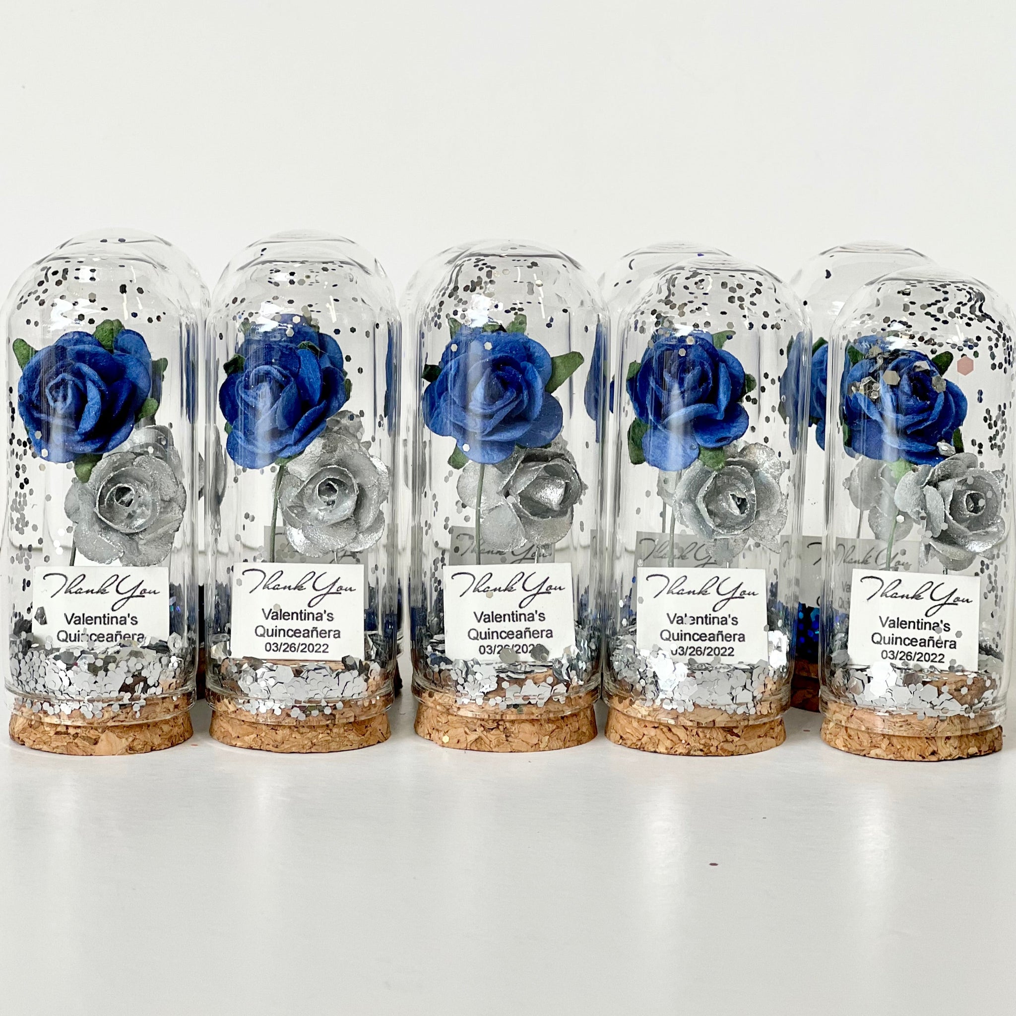 Five glass domes with preserved blue roses on a white background