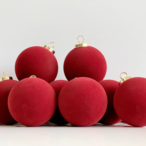 Red Christmas ornaments with gold bases on a white background