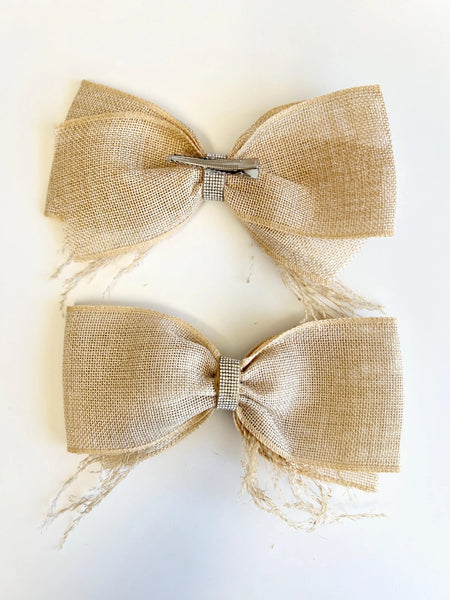 Two large burlap hair bows with frayed edges and a small silver rhinestone center band, displayed on a plain white background.