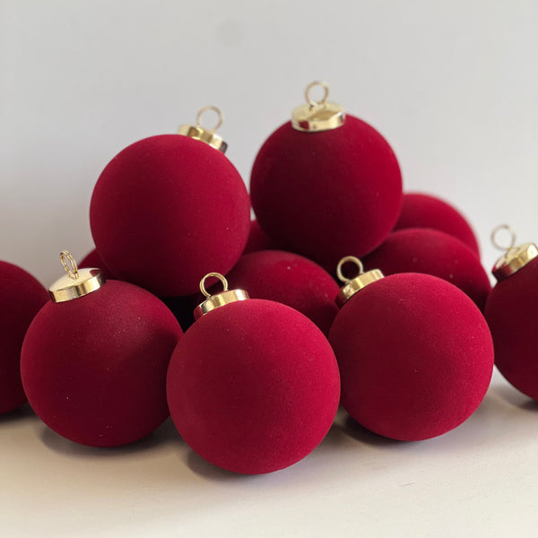 Red Christmas ornaments with gold caps on a light gray background