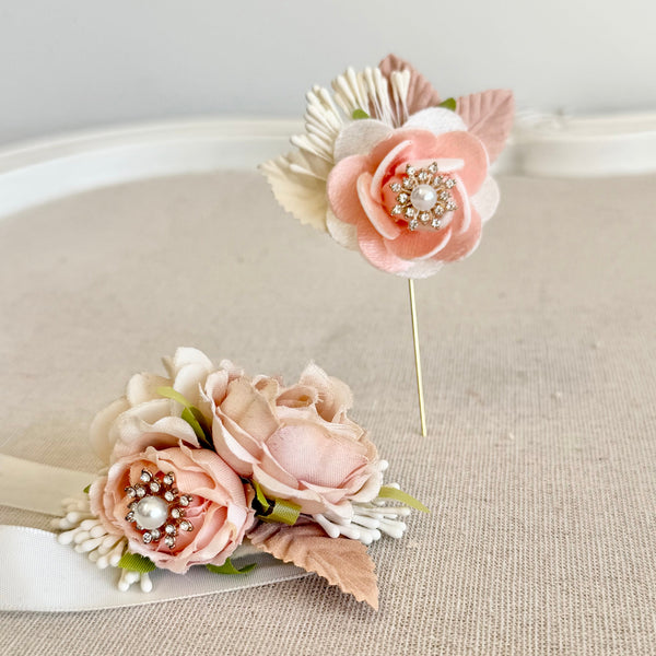 Decorative cake topper with pink flowers and a brooch on a neutral background