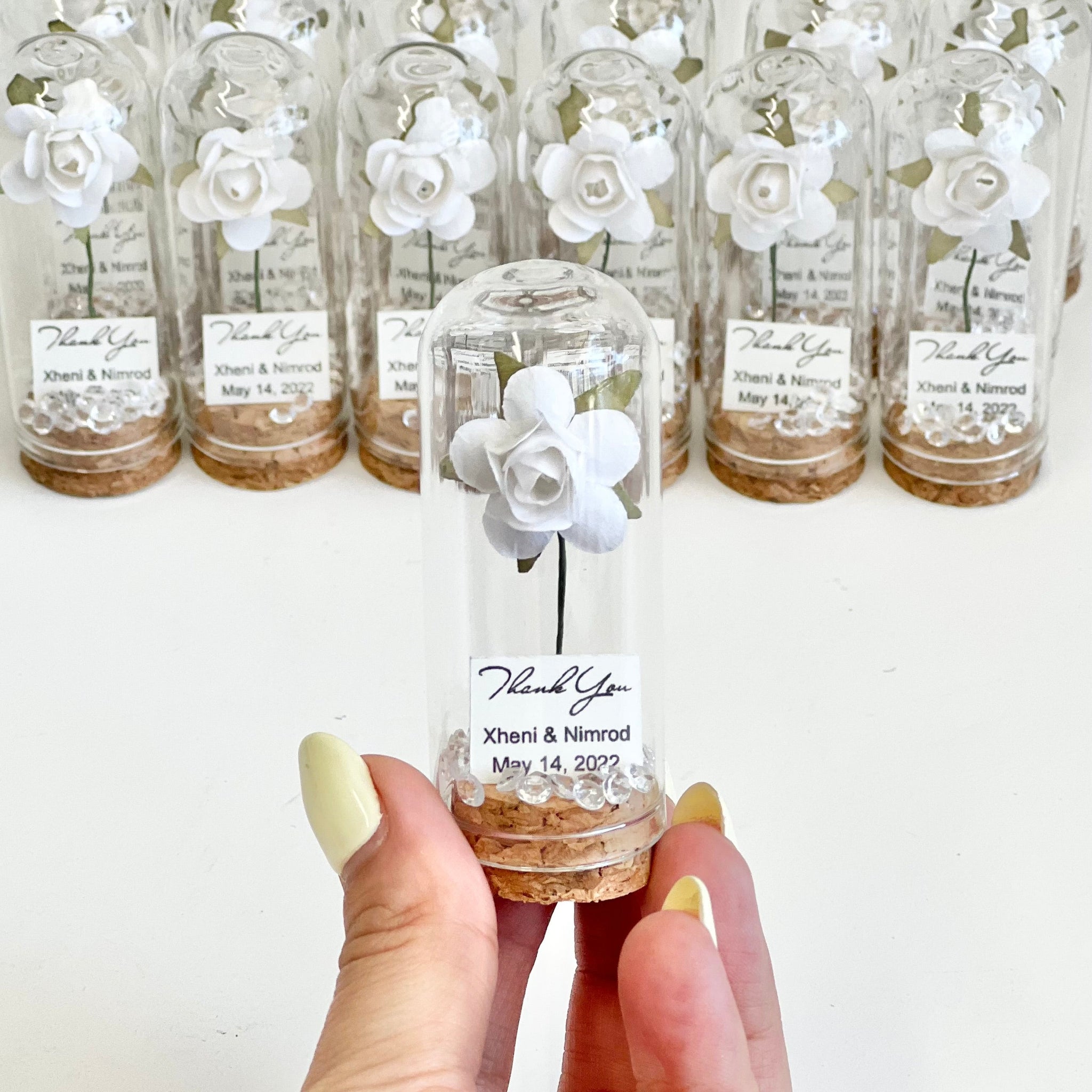 Clear glass bottles with white floral designs and labels, held by a hand.