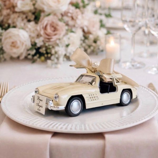 Decorative car model on a plate with flowers and candles in the background