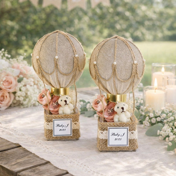 Decorative hot air balloon baby shower centerpieces with teddy bears on a table.
