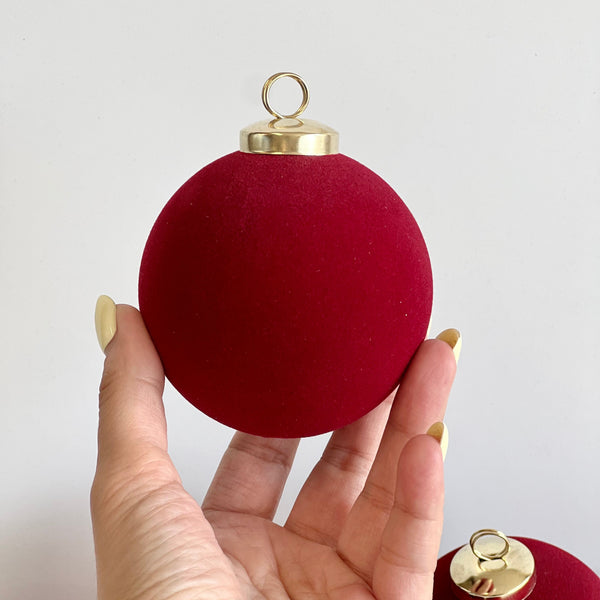 Red Christmas ornament held in a hand against a white background