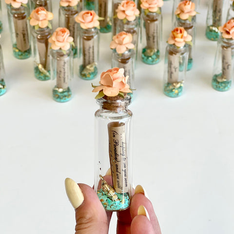 Small glass bottle with a flower inside, held by a hand against a white background