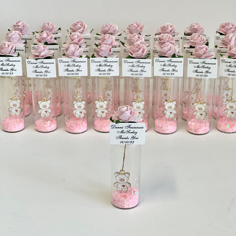 Decorative vials with pink flowers and small bears on a white background