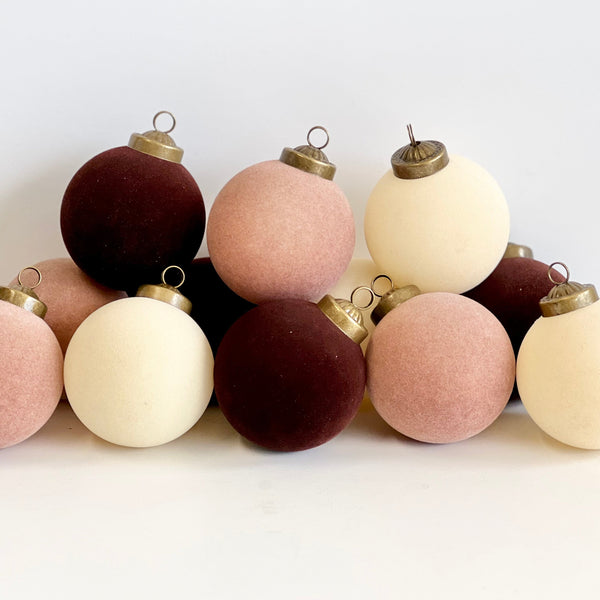 Set of round, fabric-covered Christmas ornaments in brown, pink, and white on a white background.