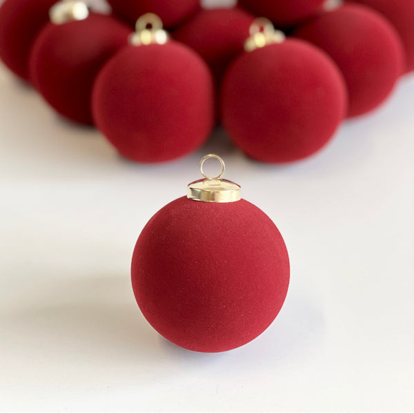 Red Christmas ornaments with gold caps on a white background