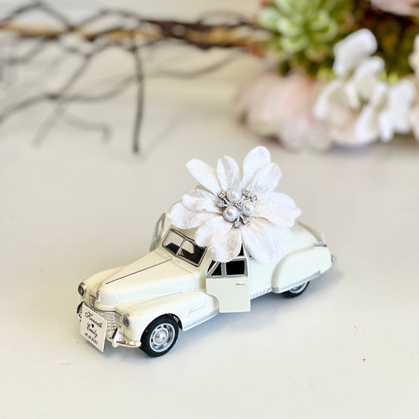 Small model car with a decorative flower on a light background