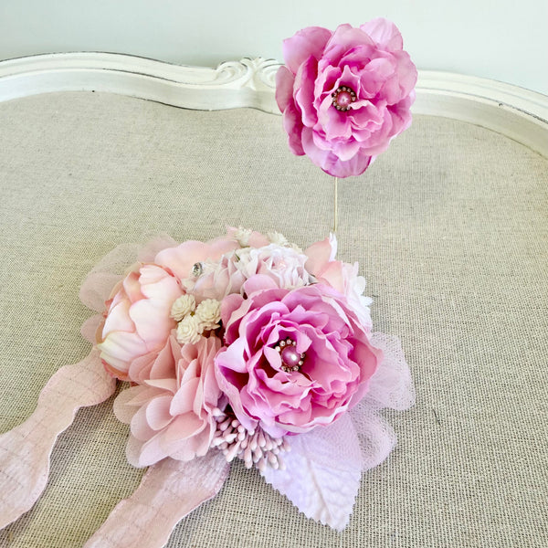 Pink floral corsage on a textured surface with a white background