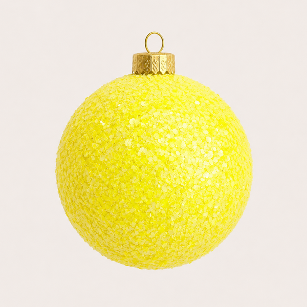 A bright yellow glitter Christmas ornament with a gold cap and hanging loop, centered against a light off-white background.