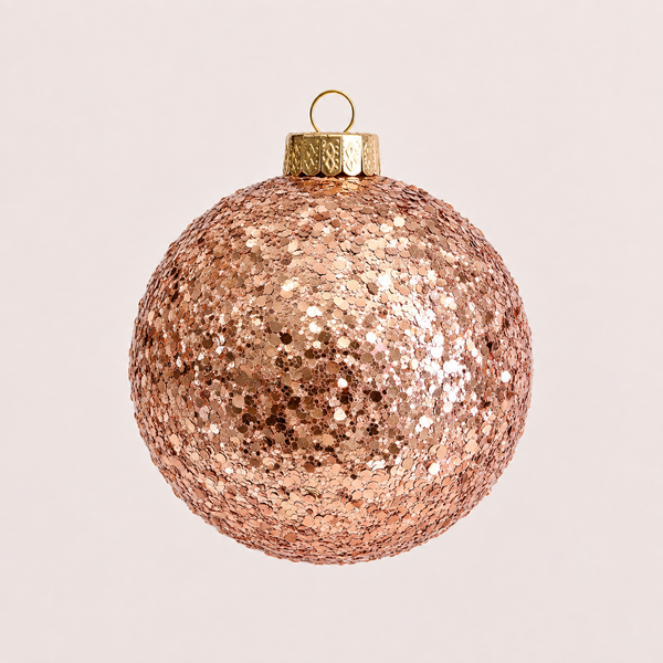 A round rose gold sequin Christmas ornament with a textured metallic cap and gold hanging loop, shown against a solid light beige background.