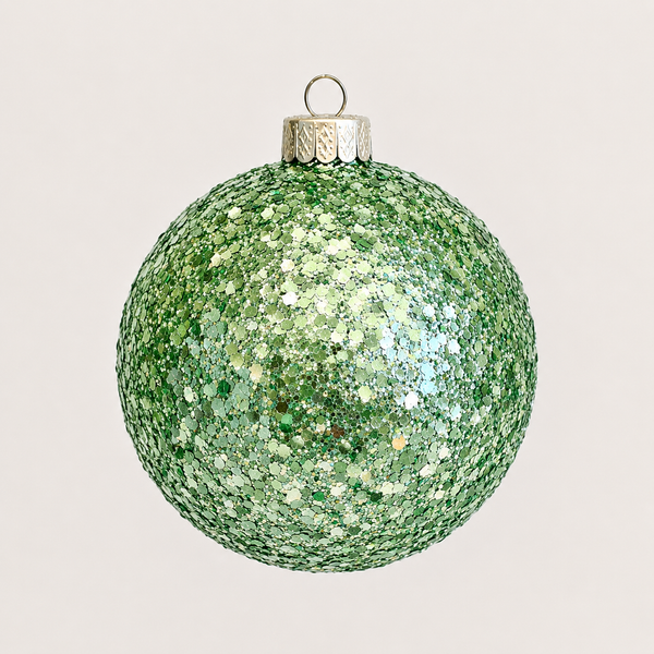 A green glitter Christmas ornament ball with a silver cap and hanging loop, shown against a plain light gray background.