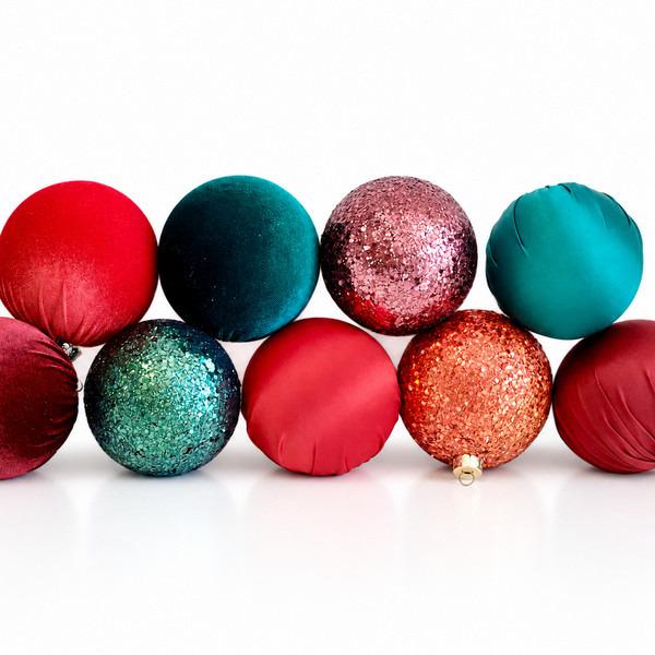 Nine Christmas ornament balls in assorted colors and textures, including red, teal, pink glitter, and orange glitter, arranged in two rows on a white background.