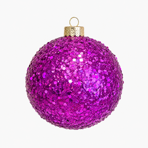 A spherical Christmas ornament covered in dense magenta and purple glitter, featuring a textured gold cap and a gold hanging loop, set against a plain white background.