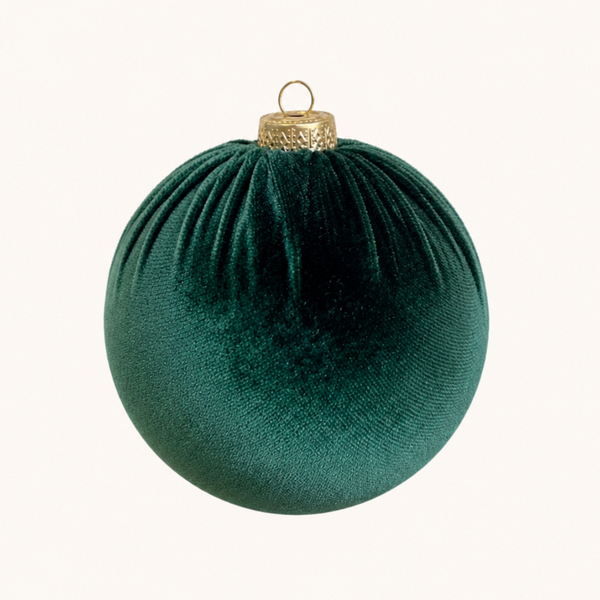 A dark green velvet Christmas bauble ornament with a gold cap and hanging loop, centered on a plain off-white background.