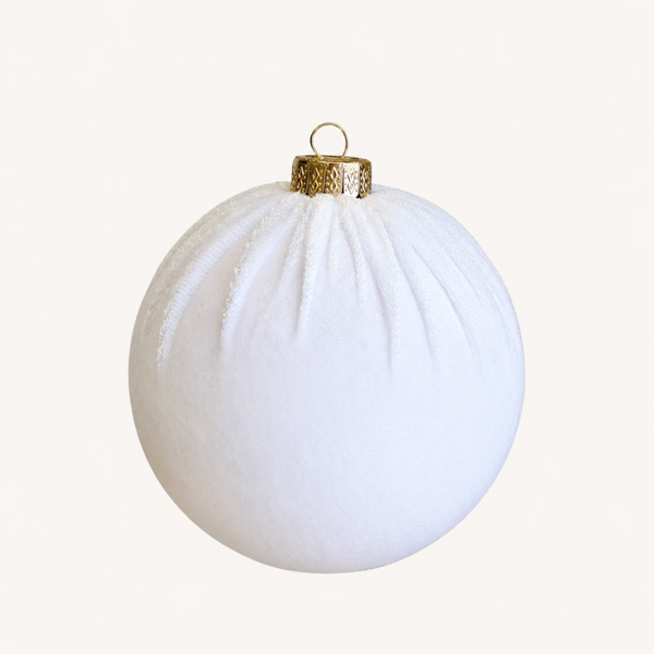 A white textured spherical Christmas ornament with a gold metallic cap and hanging loop, centered on a light cream background.