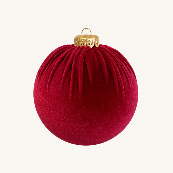 A deep red velvet Christmas ornament with a textured gold cap and hanging loop, centered on a clean off-white background.