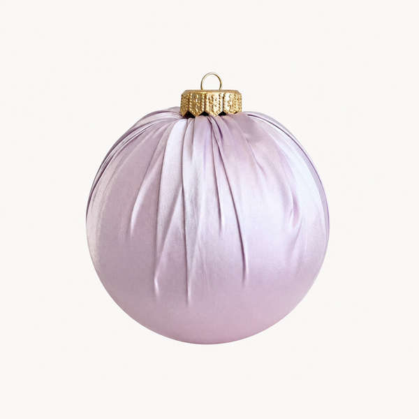 A light lavender purple Christmas ornament with a textured gold cap and hanging loop, shown against a plain off-white background.