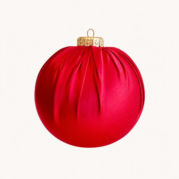 A red Christmas ornament shaped like a ribbed sphere with a gold hanging loop and textured cap, shown against a plain off-white background.
