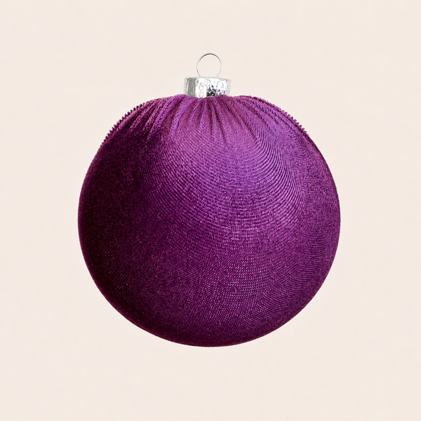 A textured purple Christmas ornament with a silver hanging cap, shown against a solid light beige background.