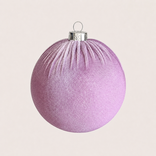 A spherical lavender Christmas ornament with a textured, ribbed fabric-like surface and a silver hanging cap, shown against a solid light beige background.