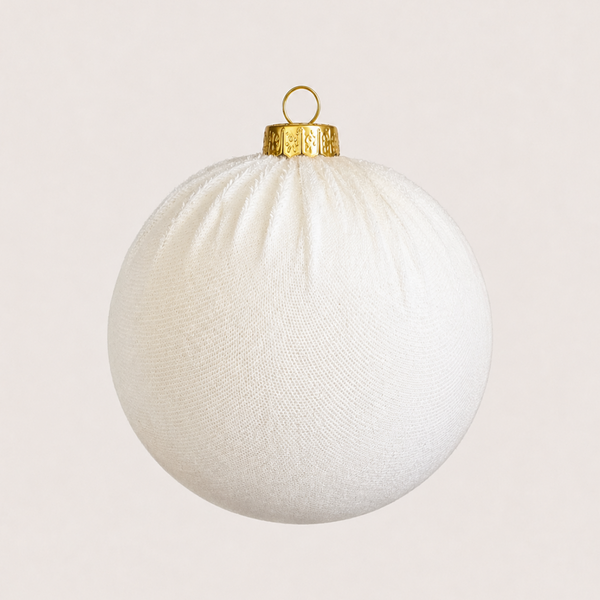 A white textured fabric Christmas ornament with a gold metal cap and hanging loop, shown against a solid light beige background.
