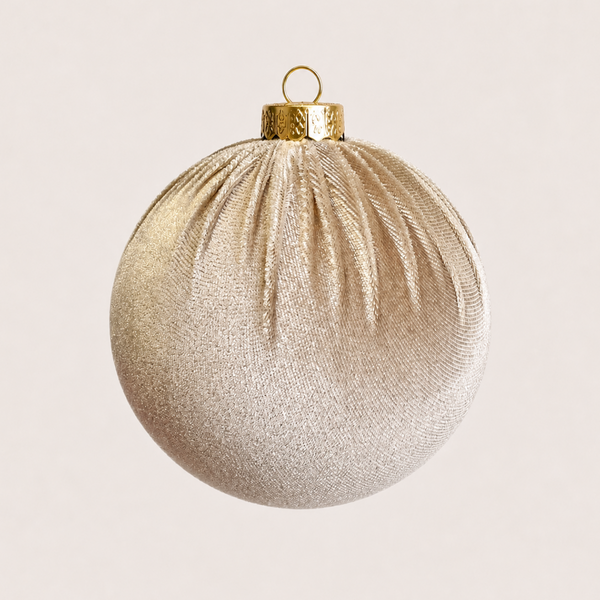 A spherical Christmas ornament with a textured, ribbed metallic gold surface and a hammered gold cap with a hanging loop, shown against a solid off-white background.