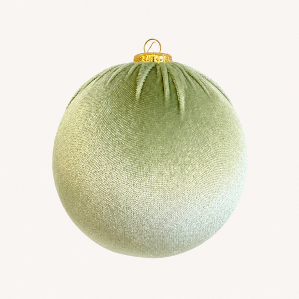 A spherical Christmas ornament in a textured sage green fabric with a gold hanging loop at the top, shown against a plain off-white background.