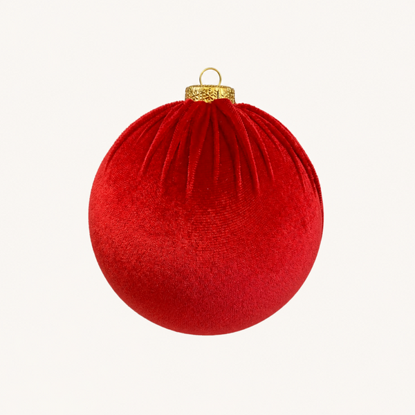 A red velvet Christmas bauble ornament with a gold hanging loop and cap, centered on a plain off-white background.