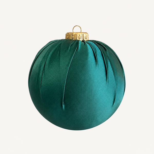 A spherical green fabric ornament with gathered pleats and a gold hanging loop at the top, shown against a plain off-white background.