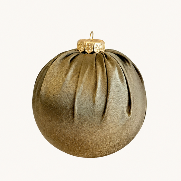 A metallic gold Christmas ornament shaped like a pleated sphere with a textured cap and hanging loop, shown against a plain off-white background.