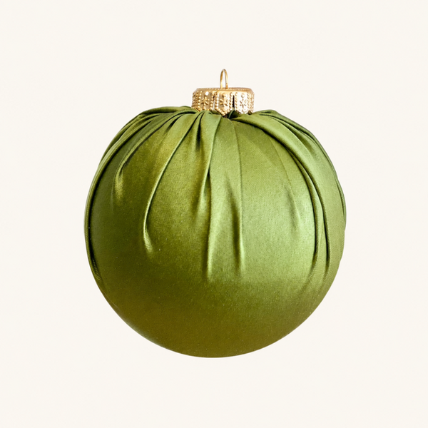 An olive green pleated fabric Christmas ornament with a gold hanging loop and cap, shown against a plain off-white background.